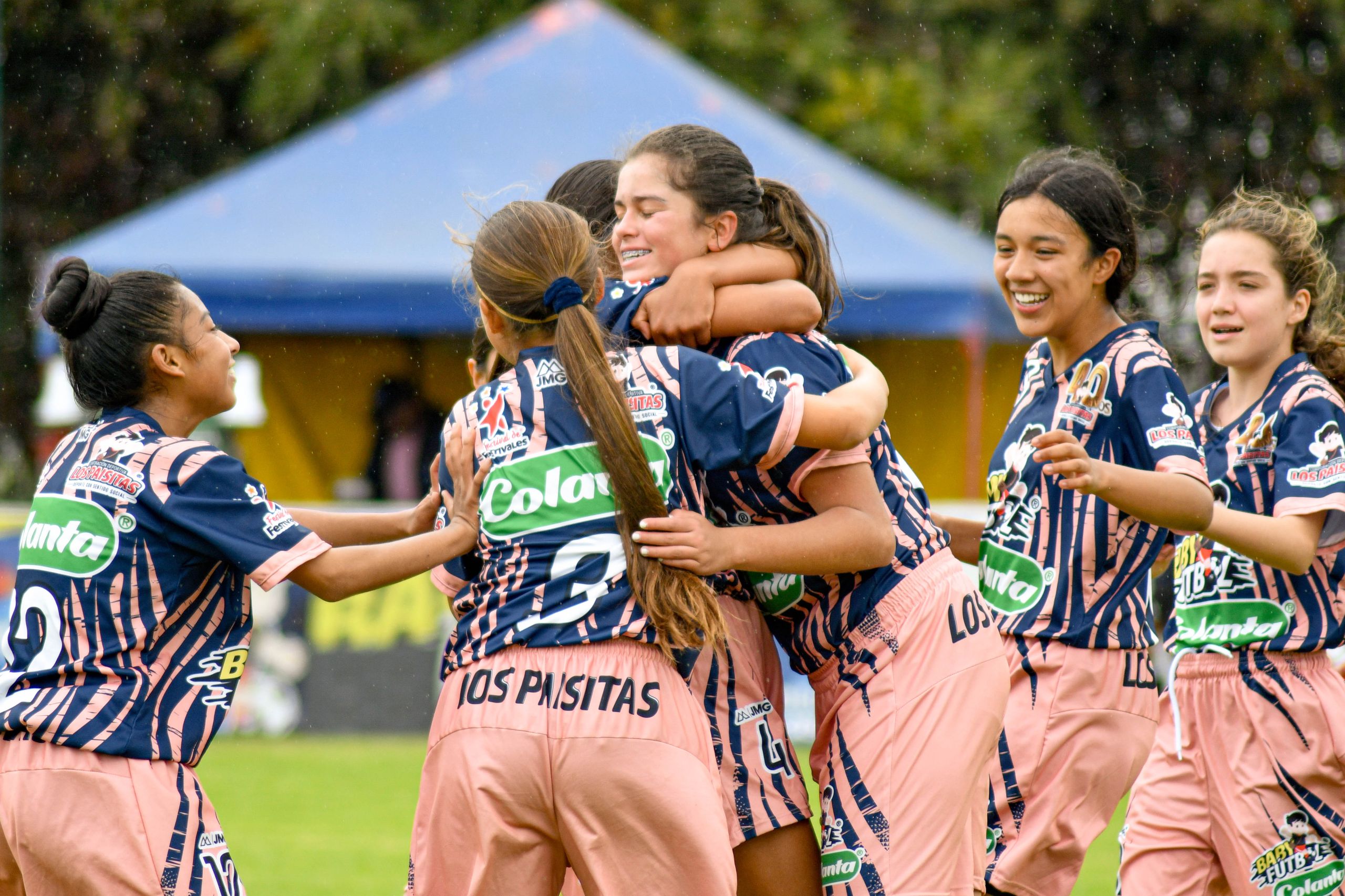 Teenage girls' soccer team celebrating together on the field outdoors.